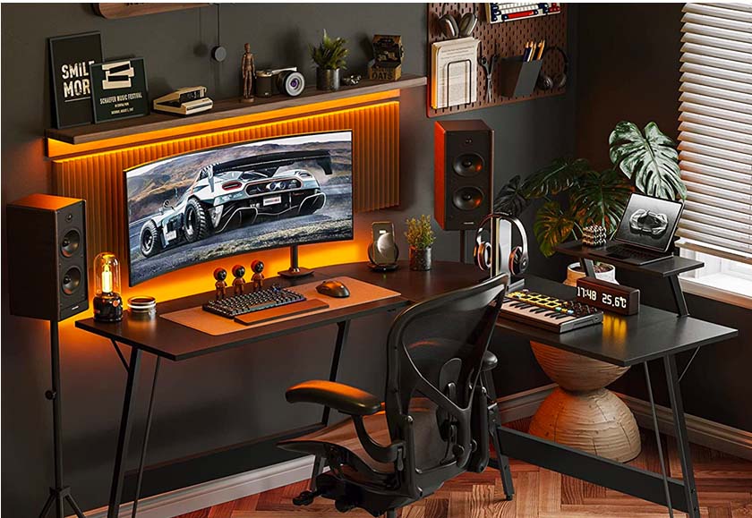 Cubiker Gaming L-Shaped Desk with mobile shelf, on which there is a laptop. On the table there is a panoramic monitor, a musical keyboard, a headset and other accessories and decorative elements.