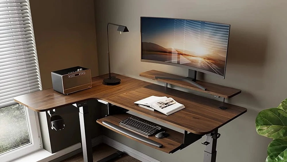 Escritorio para computadoras en forma de L, con soporte elevador para el monitor, bandeja retr&aacute;ctil para el teclado y patas ajustables en altura.